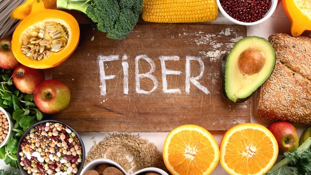 fiber rich  vegetables and fruit around a cutting board