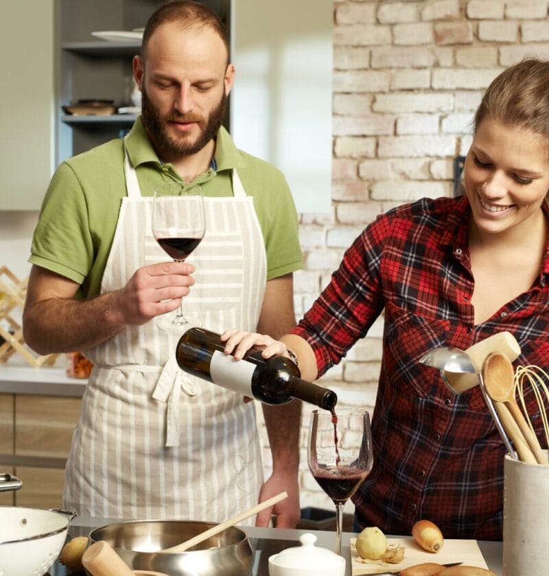 couple drinking and pouring wine in the kitchen red wine