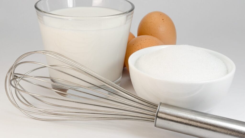 sugar, eggs, milk, and whisk